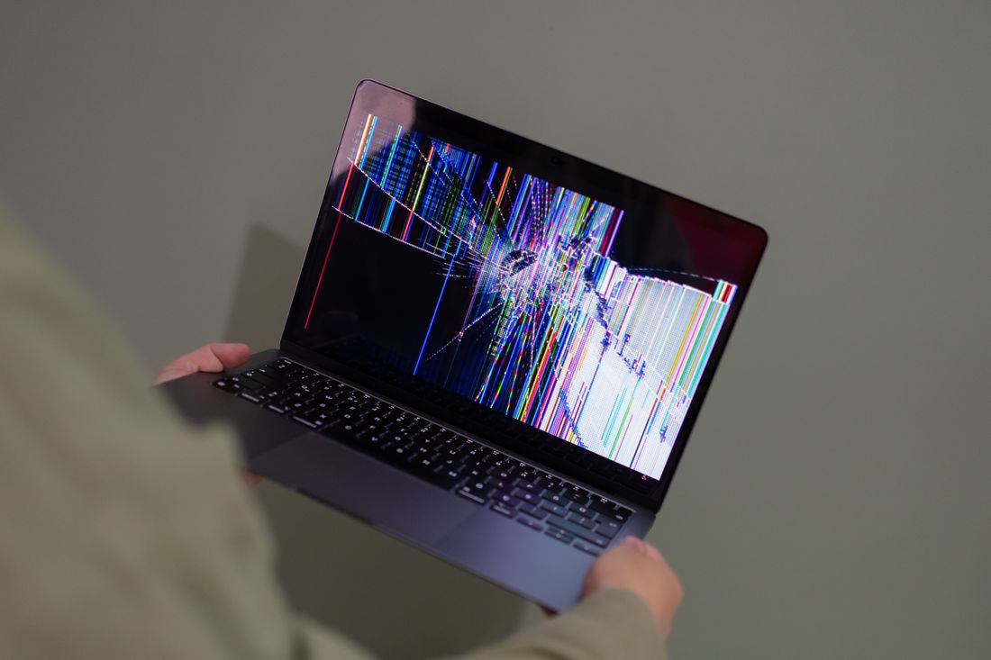 Cracked laptop screen being assessed for repair